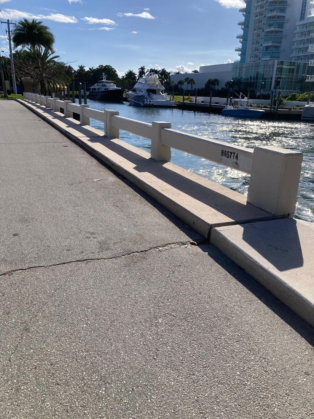 Existing West Lake Drive bridge rail, stenciled with bridge number 865774, over calm water